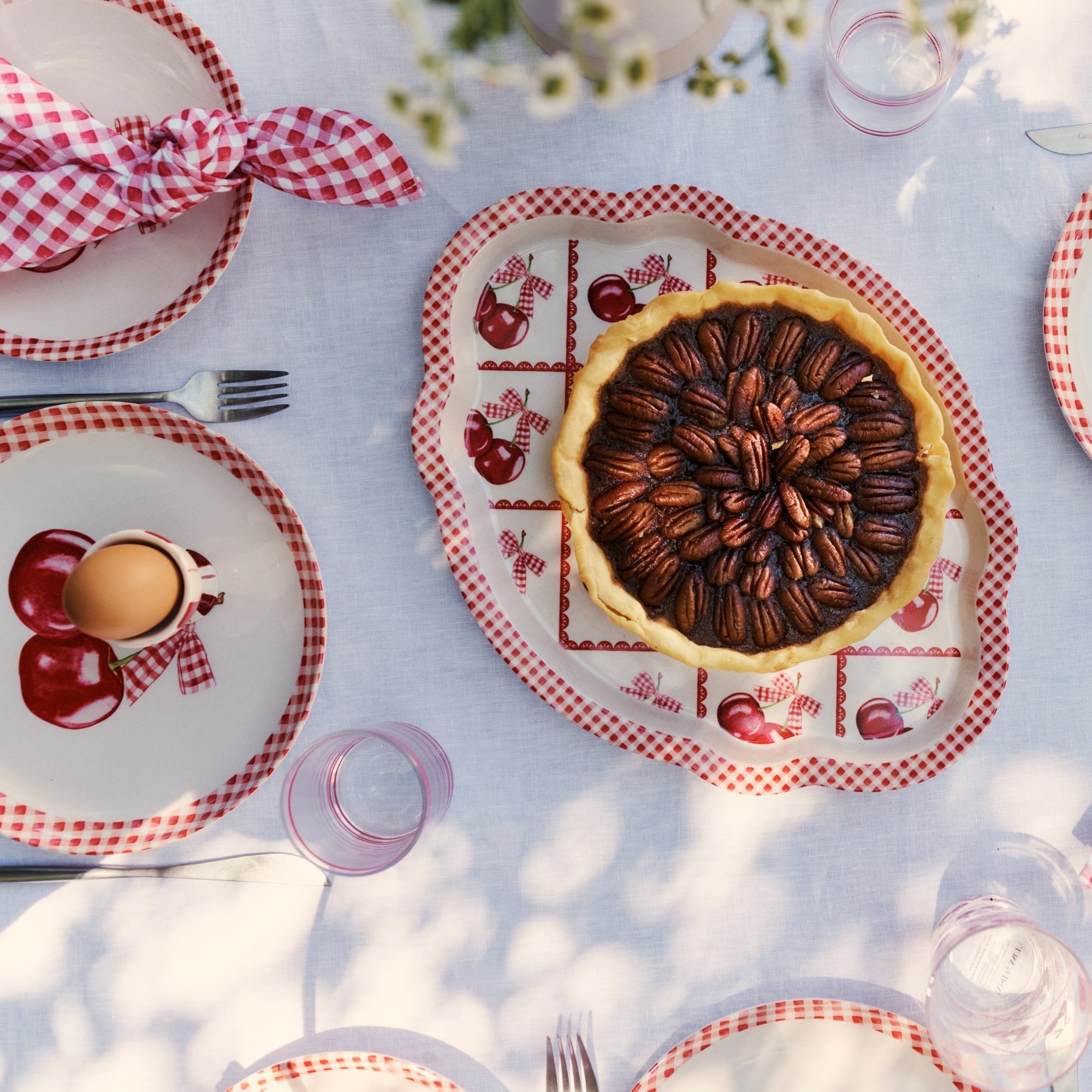 various dishware with red and white gingham and cherry themed pattern print