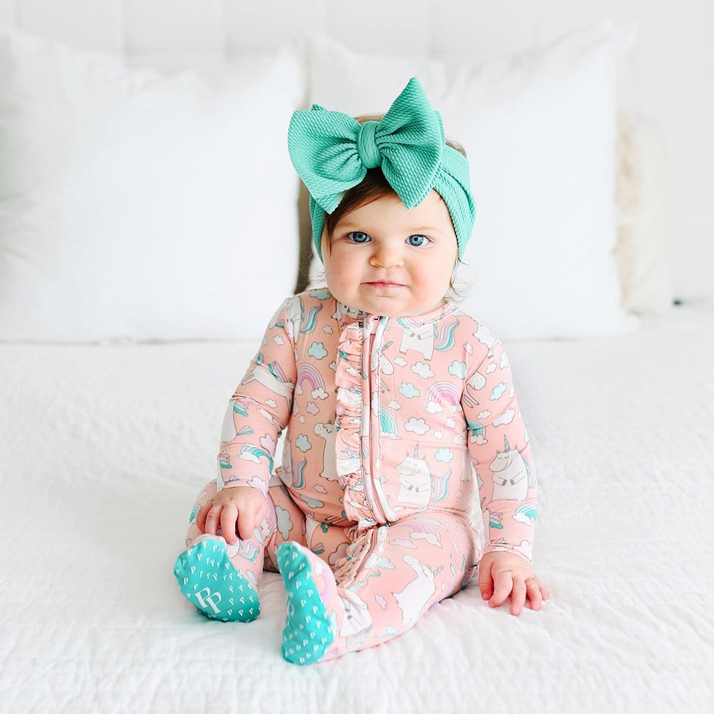 Sitting baby wearing pink Olive Footie Ruffled Zippered One Piece