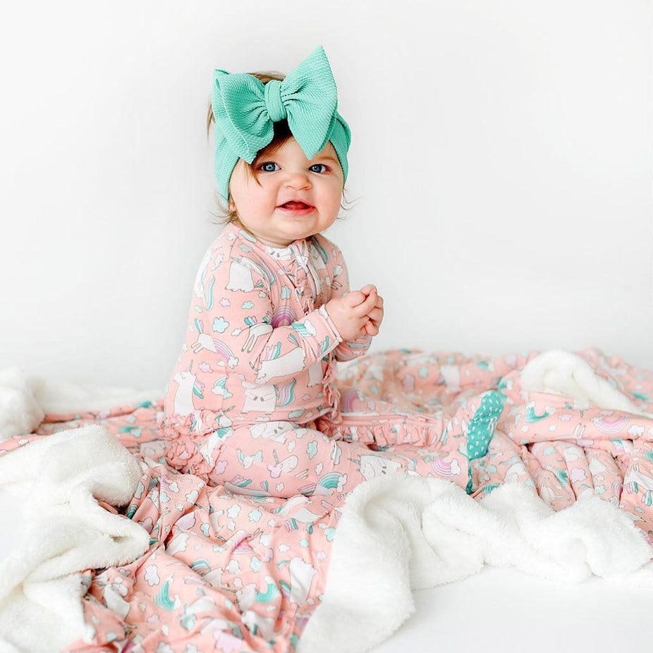Baby wearing pink Olive & Off White Plush Patoo with unicorn pattern