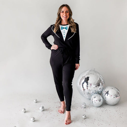 Woman in Tuxedo Pajamas for Women with New Year's Eve Ball behind her