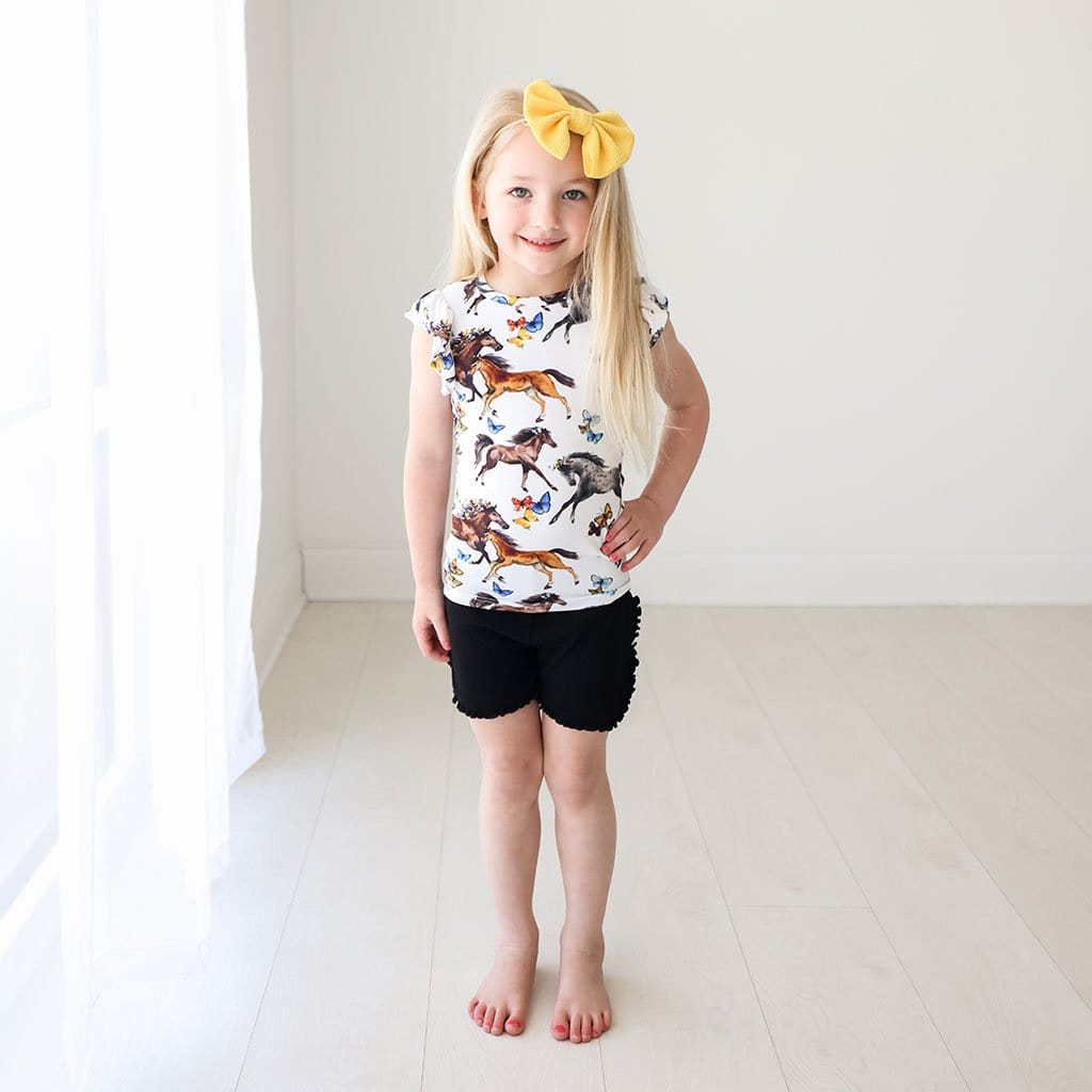 Toddler wearing yellow ribbon wearing Claire Ruffled Cap Sleeve Top Ruffled Short Set