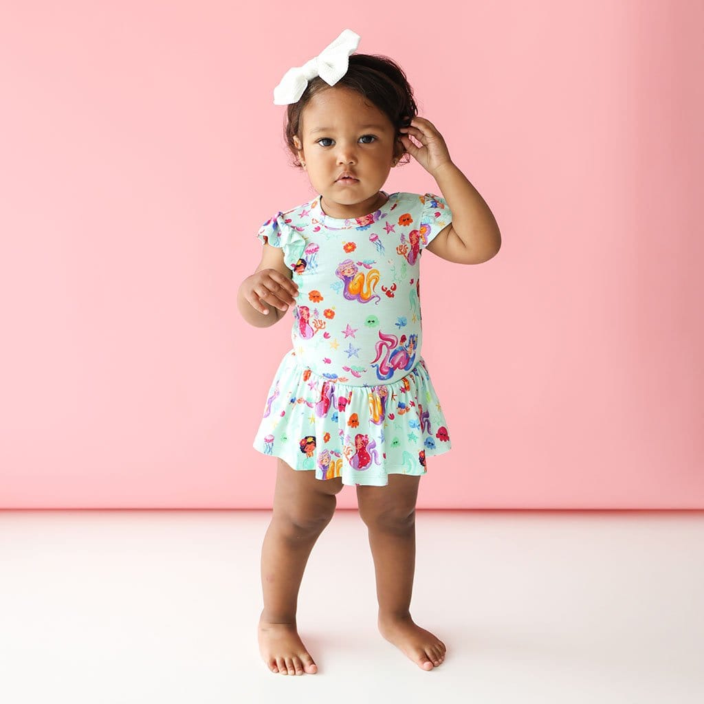 Baby girl in white ribbon wearing Kai Ruffled Cap Sleeve Twirl Skirt Bodysuit