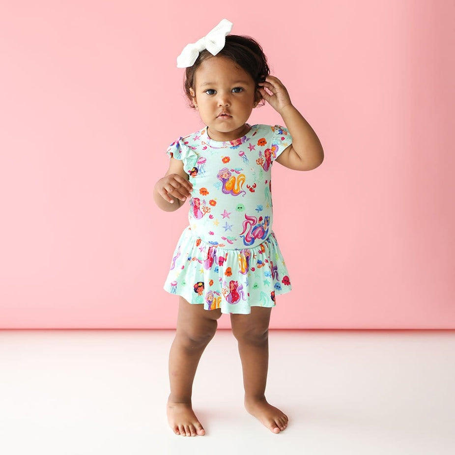 Baby girl in white ribbon wearing Kai Ruffled Cap Sleeve Twirl Skirt Bodysuit