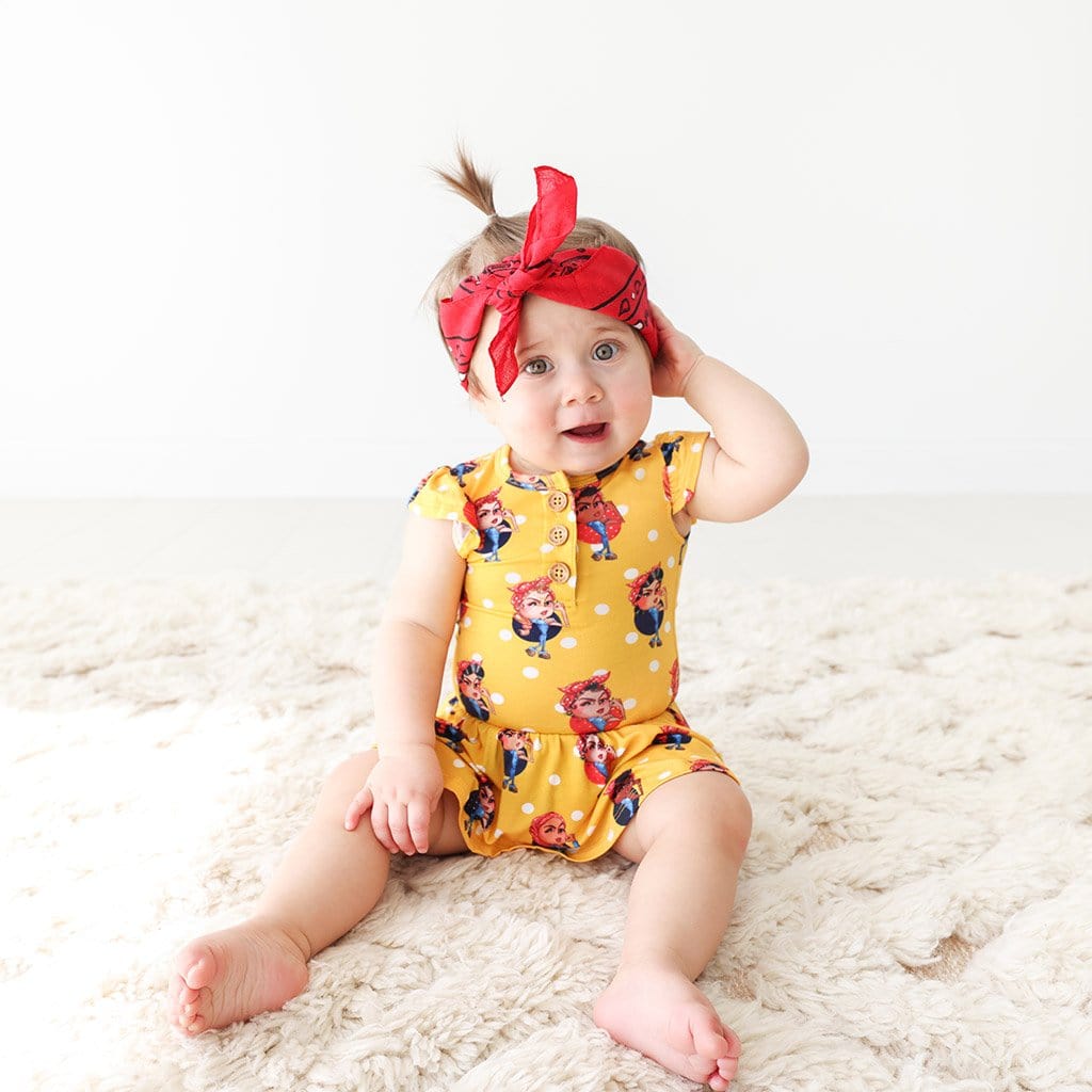 Baby sitting wearing Rosie the Riveters Ruffled Cap Sleeve Henley Twirl Skirt Bodysuit