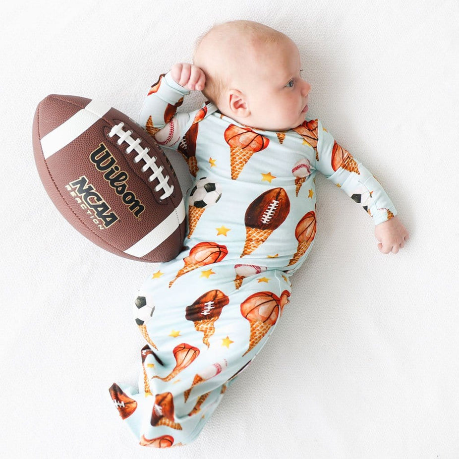 Baby beside a Football wearing Scoops Zippered Gown