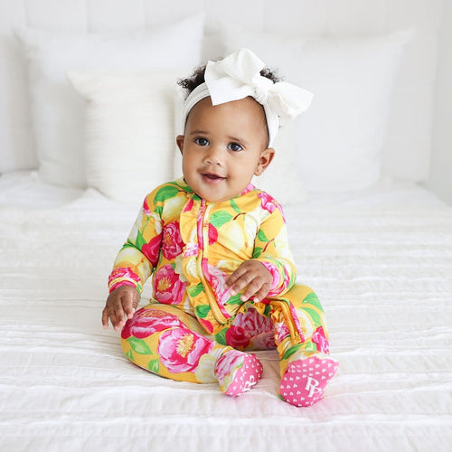 Baby in bed wearing Annika Footie Ruffled Zippered One Piece