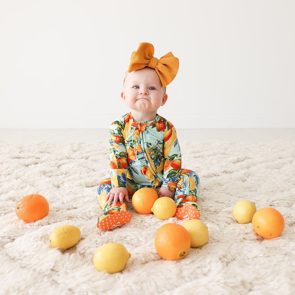 Baby wearing Lucia Footie Ruffled Zippered One Piece