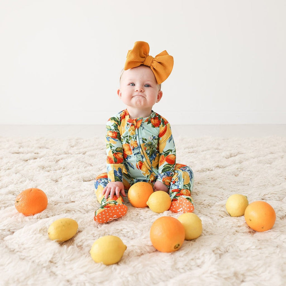 Baby wearing Lucia Footie Ruffled Zippered One Piece
