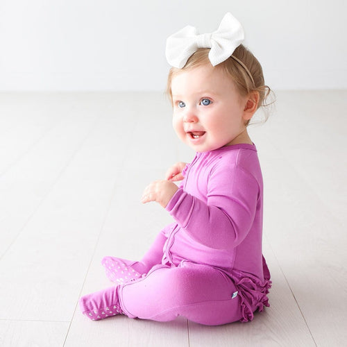 Baby in white ribbon wearing Royal Violet Footie Ruffled Zippered One Piece