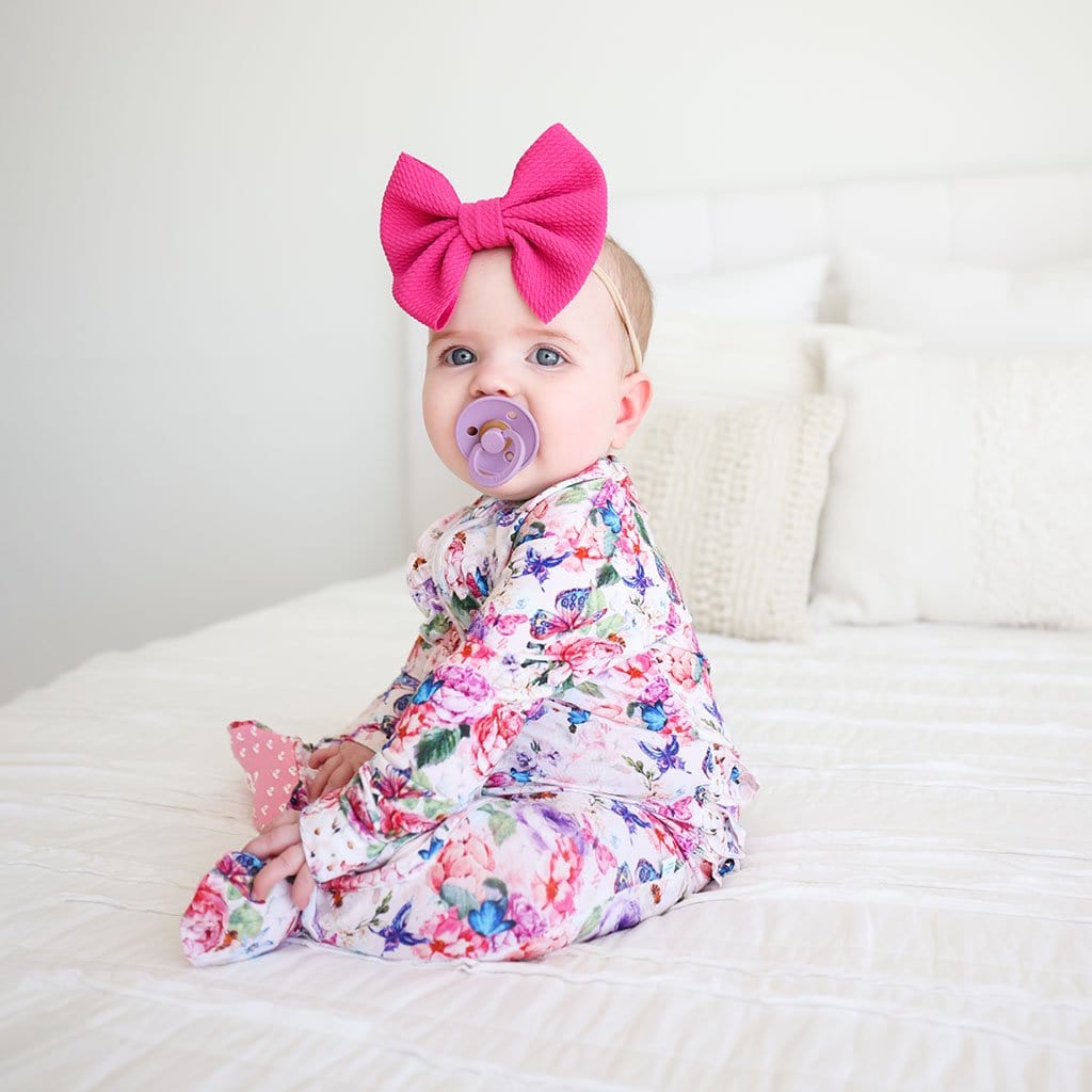 Baby on pink ribbon wearing Vivienne Footie Ruffled Zippered One Piece