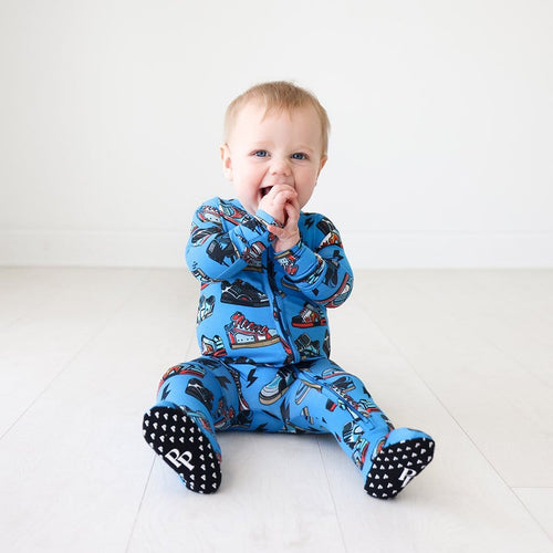 Sitting baby wearing Bolt Footie Zippered One Piece in shoe prints