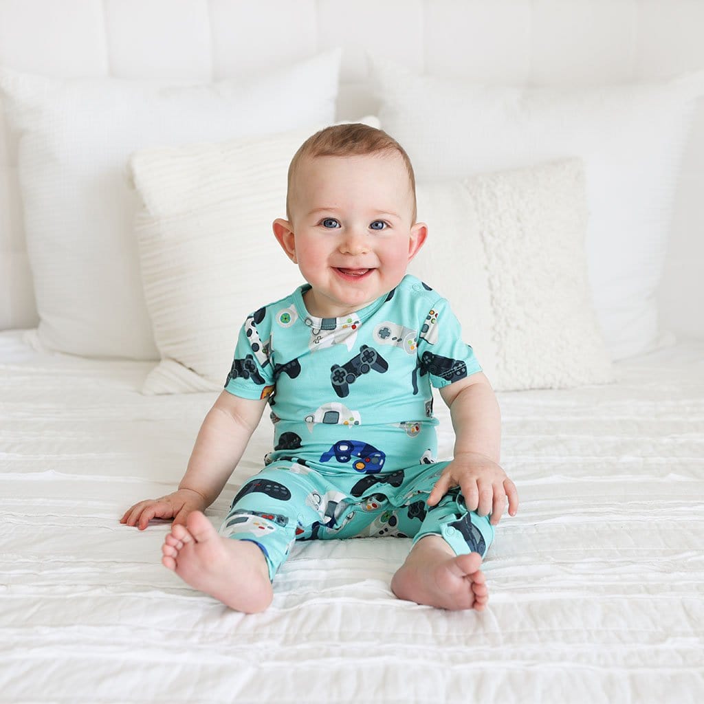 Baby sitting in bed wearing Gamer Short Sleeve Romper