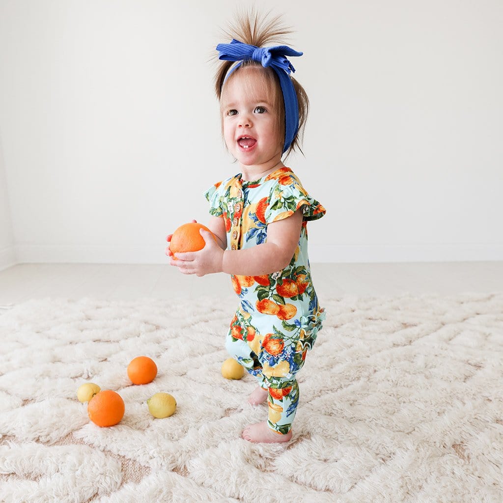 Baby wearing Lucia Ruffled Cap Sleeve Henley Romper
