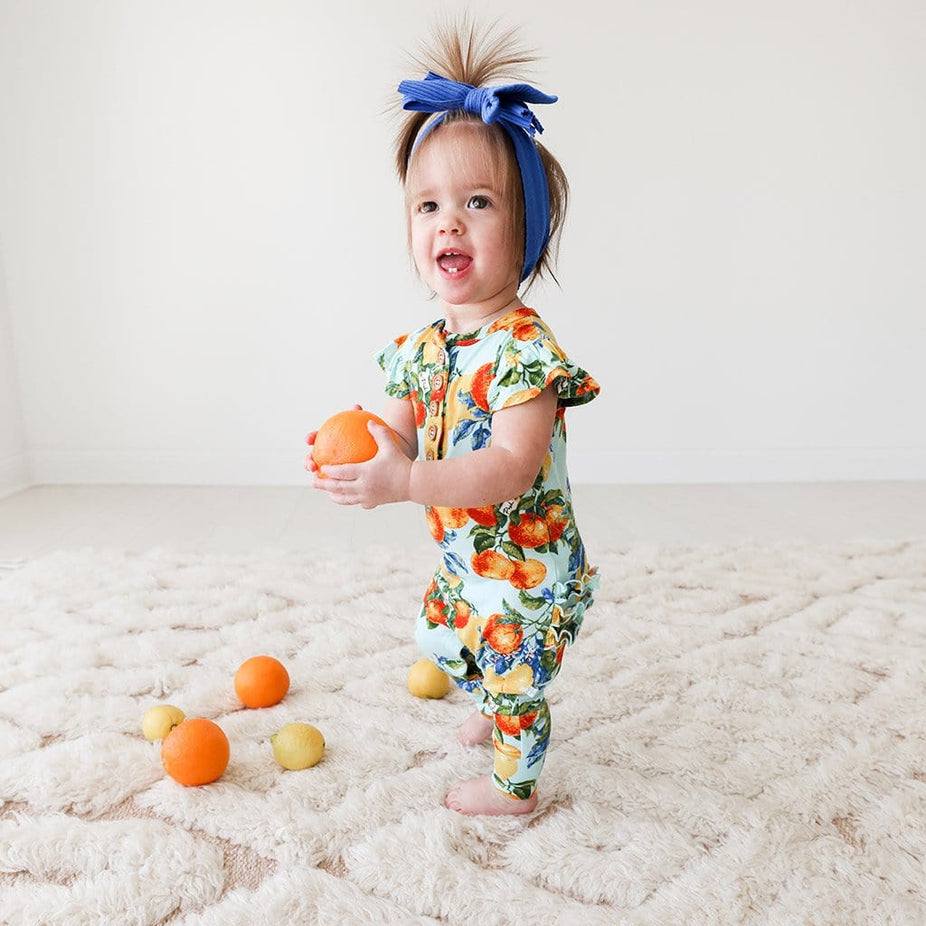 Baby wearing Lucia Ruffled Cap Sleeve Henley Romper