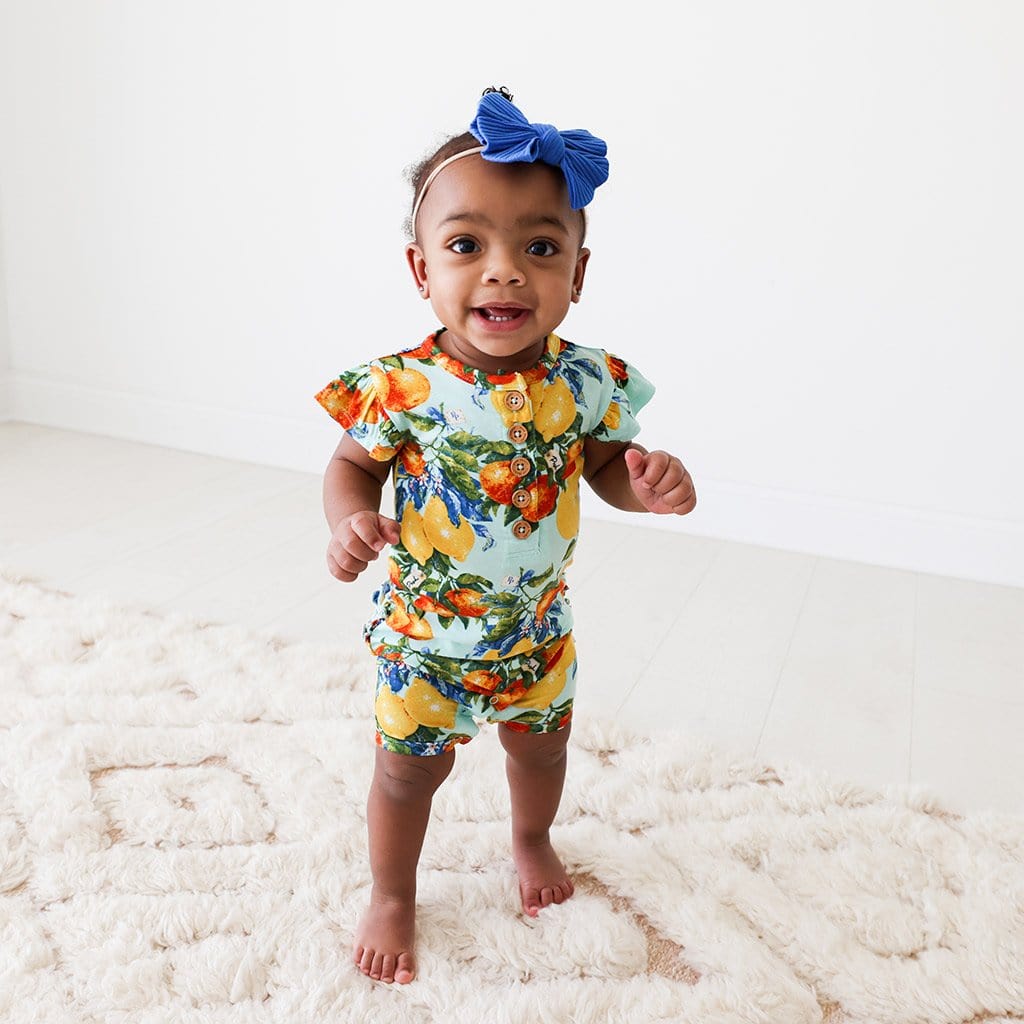 Baby wearing Lucia Ruffled Cap Sleeve Henley Short Romper