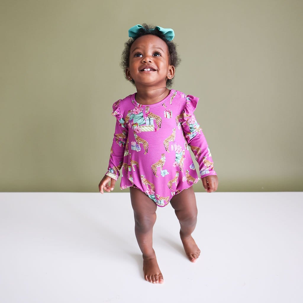 Baby Girl looking up and smiling in  a Leopard Baby Girl Bubble Romper | Keana