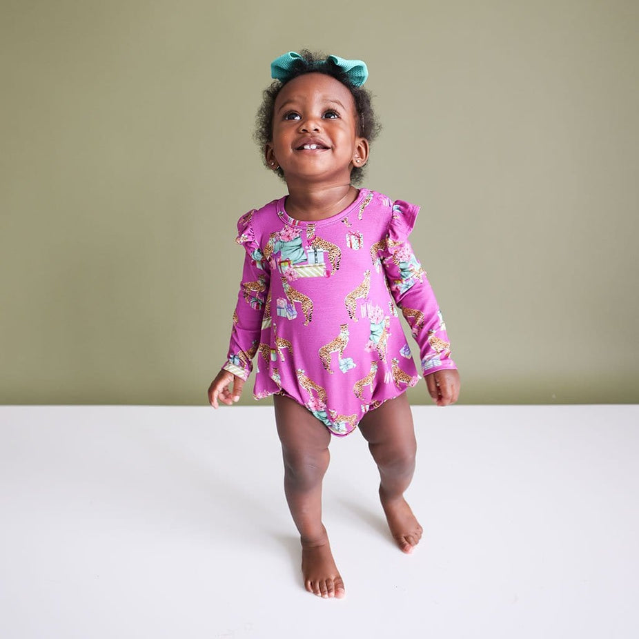 Baby Girl looking up and smiling in  a Leopard Baby Girl Bubble Romper | Keana