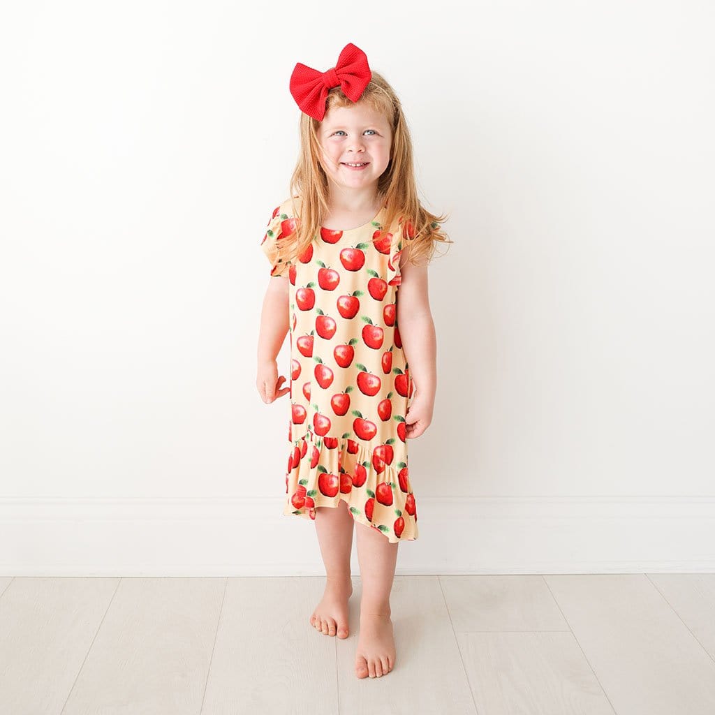 Toddler wearing apple print Finn Ruffled Cap Sleeve Hi-Low Dress
