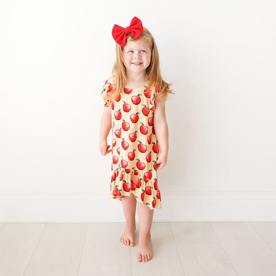 Toddler wearing apple print Finn Ruffled Cap Sleeve Hi-Low Dress